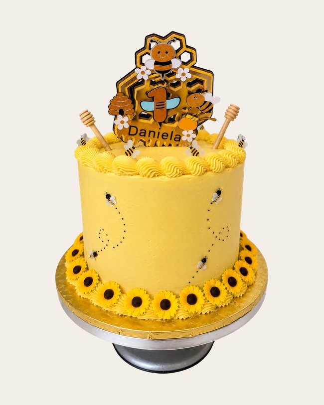 Yellow bee-themed first birthday cake with sunflowers